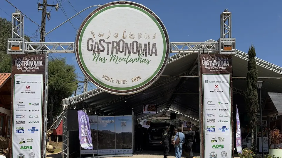 arco de entrada do evento com placa circular 'Gastronomia nas Montanhas' e estrutura de tendas