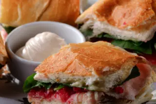 hambúrguer com queijo, crocante de bacon e maionese ao lado de lata de refrigerante e caixa de batatas