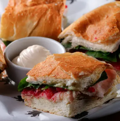 hambúrguer com queijo, crocante de bacon e maionese ao lado de lata de refrigerante e caixa de batatas