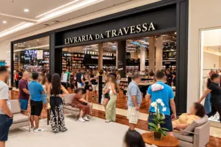 Entrada da Livraria da Travessa no shopping, com clientes na área externa e estantes de livros ao fundo