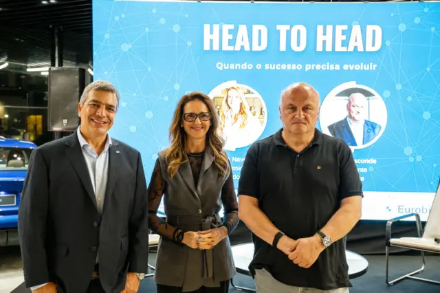 Três pessoas em pé diante de painel azul com o texto 'HEAD TO HEAD' e subtítulo 'Quando o sucesso precisa evoluir'.
