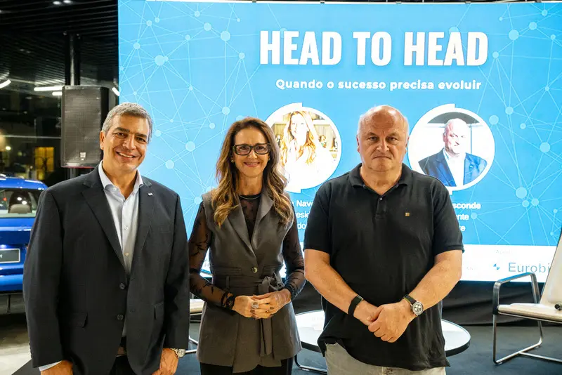 Três pessoas em pé diante de painel azul com o texto 'HEAD TO HEAD' e subtítulo 'Quando o sucesso precisa evoluir'.