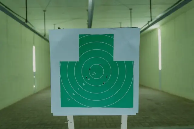 Alvo circular verde com marcas de disparos em estande de tiro