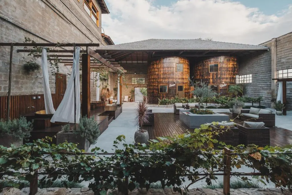 pátio interno com dois grandes tonéis de madeira, áreas de estar e plantas decorativas
