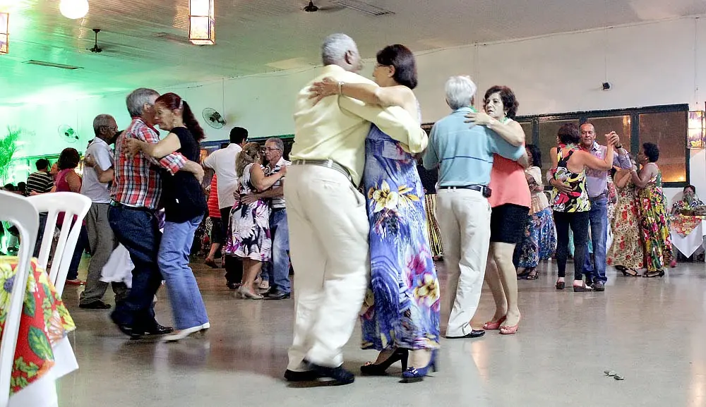 Casais dançando próximos uns dos outros em pista de dança interna