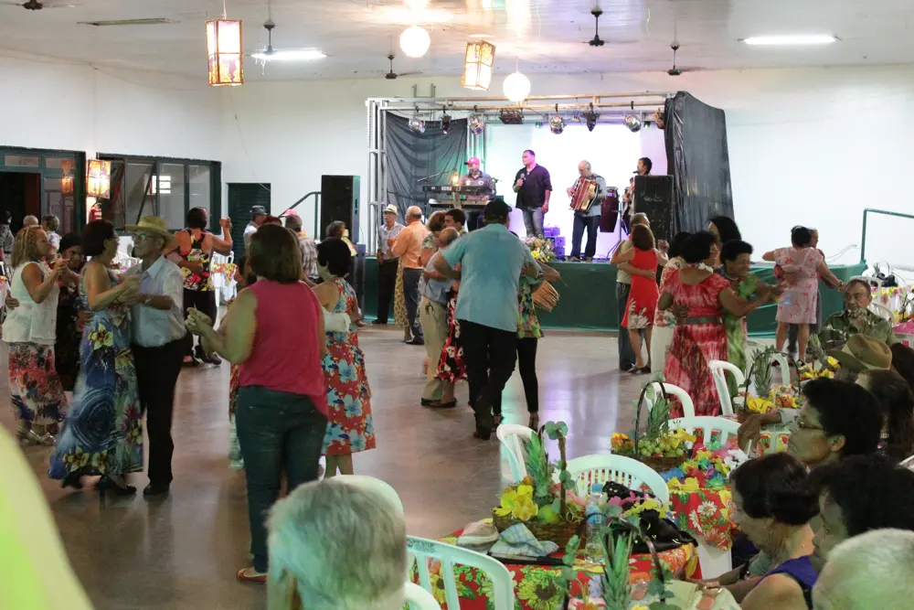 Banda em palco e pessoas dançando em frente ao palco em salão amplo