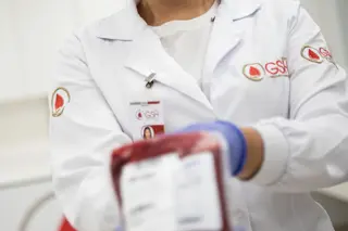profissional de saúde com jaleco branco do GSH segurando uma bolsa de sangue com etiqueta