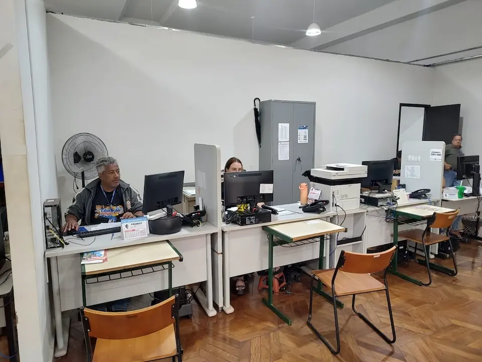 sala de atendimento com balcões, computadores e atendentes sentados